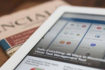 white tablet computer on top of newspaper